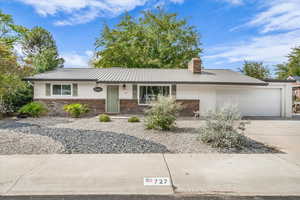 Single story home featuring brick siding, covered porch, concrete driveway, and a metal roof