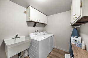 Laundry room featuring light wood finished floors, washer and clothes dryer, and cabinet space
