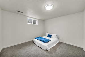 Carpeted bedroom with a textured ceiling and baseboards
