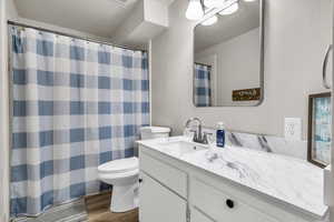 Bathroom featuring a textured wall, dark wood-type flooring, vanity, and a shower with shower curtain