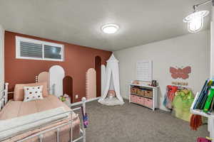 Bedroom with a textured ceiling and carpet flooring