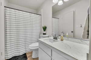 Full bath with vanity, light wood-style flooring, and curtained shower