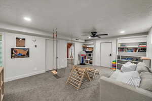 Carpeted living room with a ceiling fan and recessed lighting