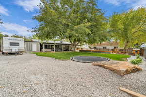 Back of house with a trampoline and a patio area