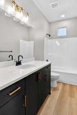 Full bath featuring vanity, light wood-style flooring, and tub / shower combination