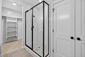 Bathroom featuring light tile patterned floors, a spacious closet, a stall shower, recessed lighting, and light colored carpet
