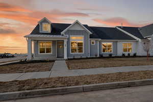 Modern inspired farmhouse with a porch, board and batten siding, and a shingled roof