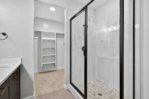 Bathroom with vanity, a walk in closet, light tile patterned floors, a shower stall, and light carpet