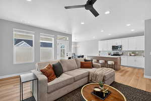 Living area with light wood finished floors, recessed lighting, a chandelier, and a ceiling fan