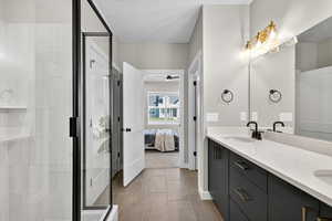 Ensuite bathroom featuring double vanity, light tile patterned floors, and a stall shower