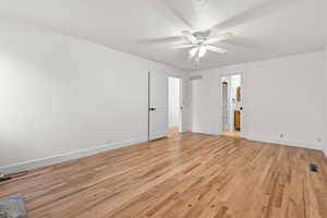 Primary bedroom with light wood finished floors, ceiling fan, and a textured ceiling