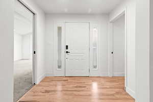 Foyer featuring light wood-type flooring and light colored carpet