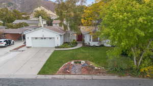 View of front of home featuring driveway, a front yard, and a garage