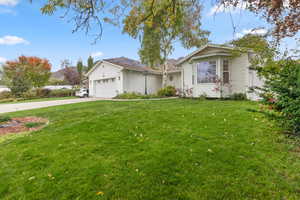 Single story home featuring a front yard, driveway, and an attached garage