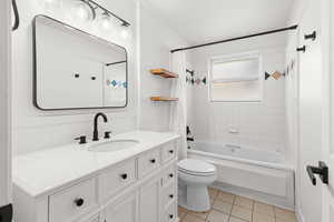 Bathroom featuring shower / bath combo with shower curtain, vanity, and light tile patterned floors