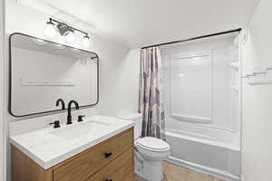 Bathroom with shower / tub combo with curtain, light tile patterned floors, and vanity