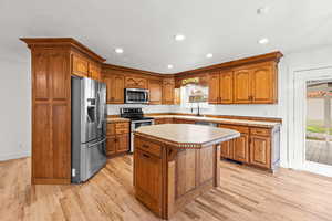 Kitchen featuring brown cabinets, stainless steel appliances, recessed lighting, light wood-style flooring, and a kitchen island