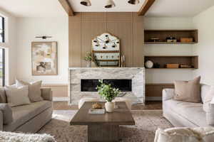 Open living room with marble-encased gas fireplace, built-ins, and west facing wall with endless windows overlooking patio.