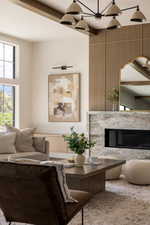 Living area featuring a textured wood-paneled accent wall, a fireplace with a stone surround, and large windows