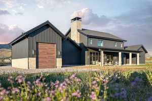 Modern farmhouse exterior featuring dark vertical siding and a prominent stone chimney