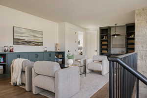 Open concept living area featuring dark wood-finish flooring, a stone accent wall, and a black metal staircase railing