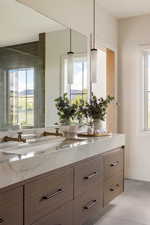 Double vanity featuring a large integrated basin, veined countertop, and wood-finish cabinetry with dark hardware