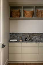 Integrated cabinetry and shelving featuring a stone backsplash and countertop, under-mount sink, and bronze-finish faucet