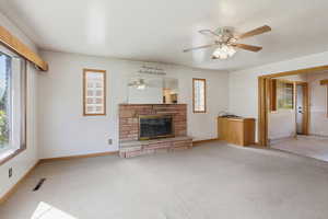 Unfurnished living room with a fireplace, carpet floors, and a ceiling fan