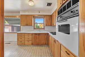 Kitchen featuring white oven, light countertops, light floors, and brown cabinets