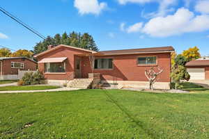 View of front facade with brick siding, a front yard, and a chimney