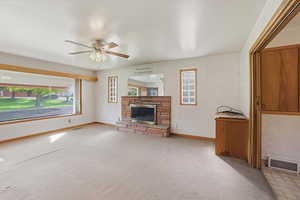 Unfurnished living room featuring a fireplace, light carpet, and ceiling fan