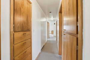Hall featuring light colored carpet and baseboards