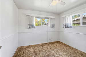 Unfurnished room featuring plenty of natural light, carpet flooring, and a ceiling fan