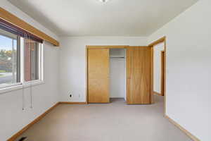 Unfurnished bedroom with light carpet and a closet
