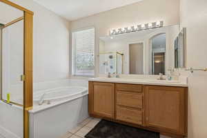 Full bath with a shower stall, a bath, light tile patterned flooring, and double vanity