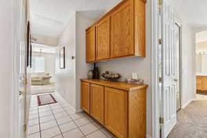 Hall with light tile patterned floors, a textured ceiling, light carpet, and arched walkways