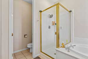 Bathroom with light tile patterned floors, a shower stall, and a garden tub