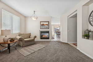 Living area with carpet, plenty of natural light, a glass covered fireplace, and tile patterned floors
