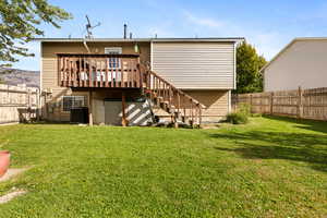 Rear view of property with a fenced backyard, a deck, and stairs