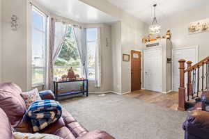 Carpeted living room with stairway, plenty of natural light, and a high ceiling