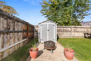 View of shed featuring a fenced backyard and an outdoor fire pit