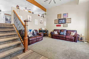Living area featuring beamed ceiling, ceiling fan, stairs, and wood finished floors