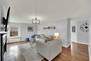 Living room with a fireplace with flush hearth, wood finished floors, and a chandelier