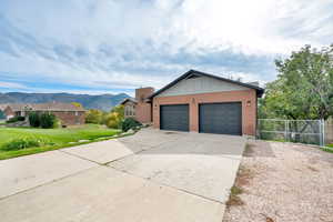 View of front of home with brick siding, a mountain view, board and batten siding, and driveway