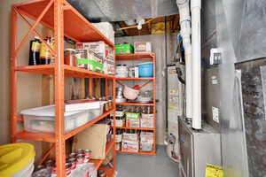Storage room featuring water heater and heating unit