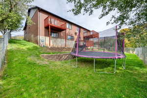 Fenced backyard featuring a trampoline