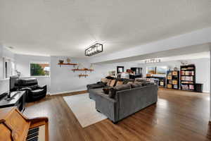 Living area featuring a textured ceiling, wood finished floors, and a chandelier