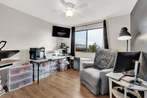 Living area featuring light wood-style floors, a ceiling fan, and a desk