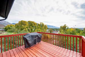 Deck with a grill, a mountain view, and view of scattered trees