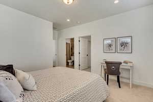 Bedroom with light colored carpet, recessed lighting, ensuite bathroom, and an office area